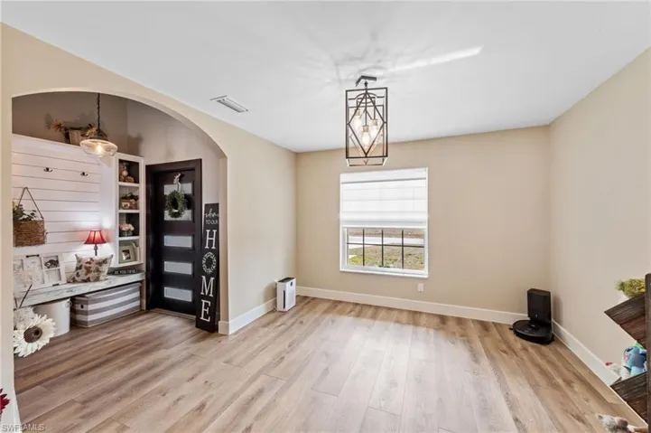 Dining room featuring light wood-style floors, arched walkways, and suspended lighting