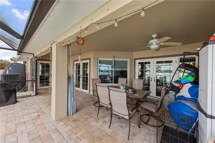 View of patio featuring french doors, outdoor dining space, ceiling fan, and a lanai