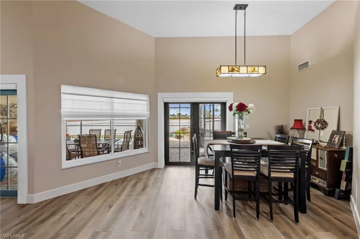 Dining room featuring light wood-style floors, a high ceiling, and french doors