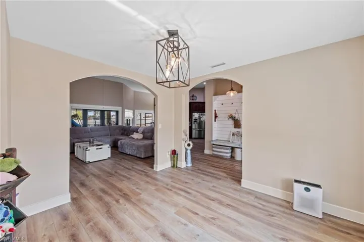 Dining area with arched walkways, light wood-style floors, and hanging lights