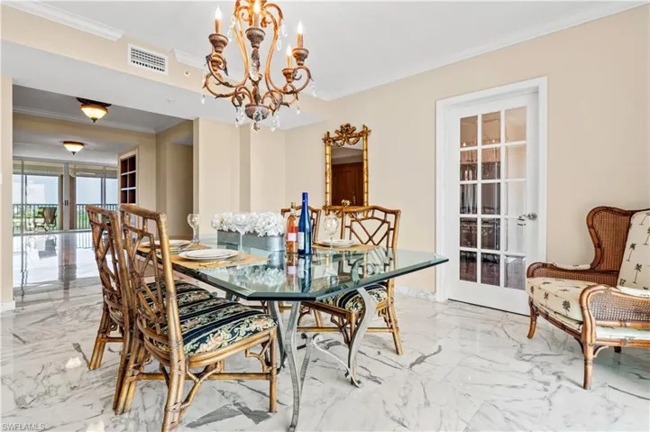 Dining room with marble tiled floors, ornamental molding, and a chandelier