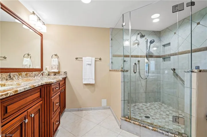 Full bathroom featuring a shower stall, double vanity, recessed lighting, and light tile patterned floors