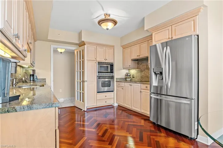 Kitchen with stainless steel appliances, light brown cabinets, light stone countertops, and tasteful backsplash