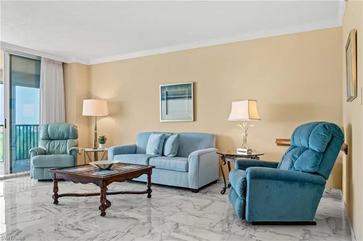 Living area with marble finish floors, ornamental molding, and expansive windows