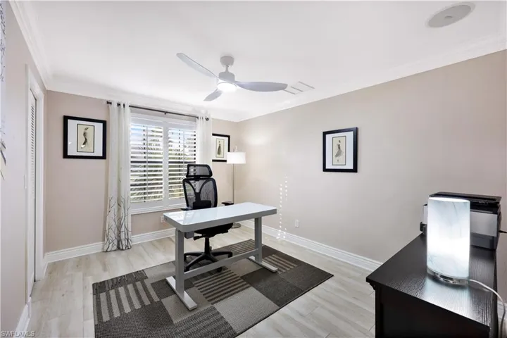Home office featuring ceiling fan, light wood-type flooring, and ornamental molding