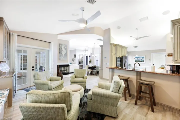 Living room with ceiling fan, french doors, sink, vaulted ceiling, and light wood-type flooring