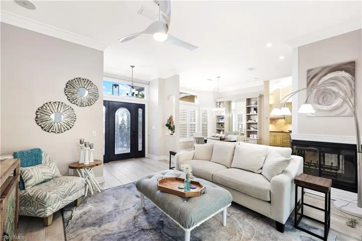 Living room featuring built in shelves, ceiling fan, and crown molding