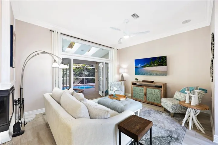 Living room with ceiling fan, light hardwood / wood-style floors, and a fireplace