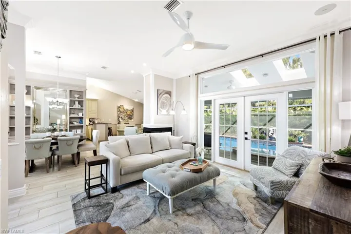Living room with crown molding, french doors, and ceiling fan with notable chandelier