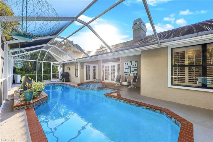 View of pool with an in ground hot tub, french doors, a lanai, grilling area, and a patio