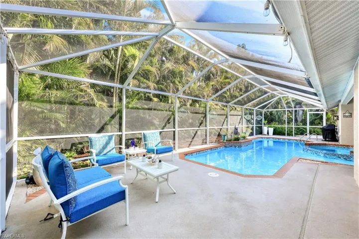 View of swimming pool with glass enclosure, a grill, and a patio area