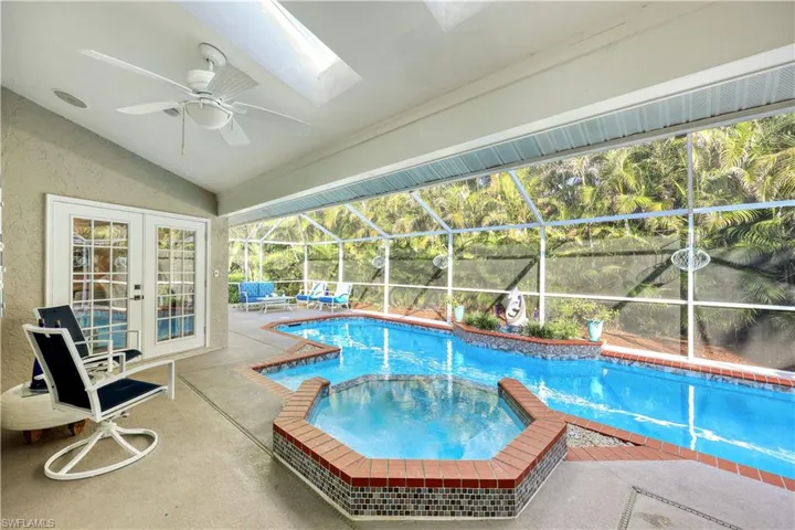 View of swimming pool featuring a patio area, ceiling fan, and glass enclosure