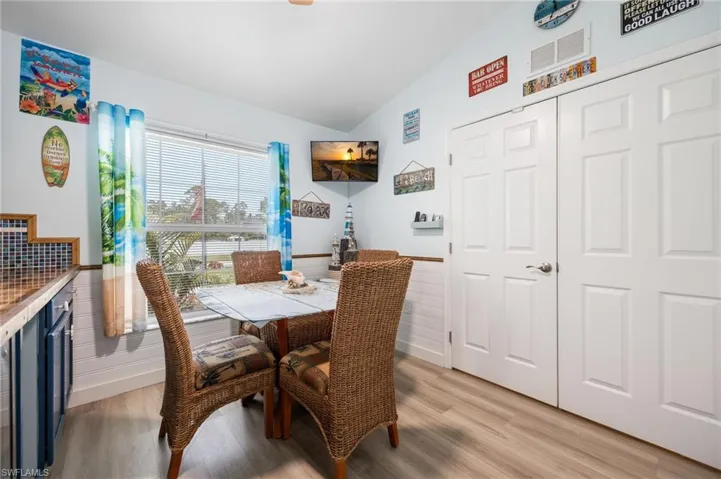 Dining area featuring light wood-finish flooring, a window with horizontal blinds, and a built-in counter with a mosaic tile backsplash