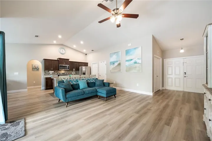 Spacious living area featuring wood-finish flooring, vaulted ceilings, and recessed lighting