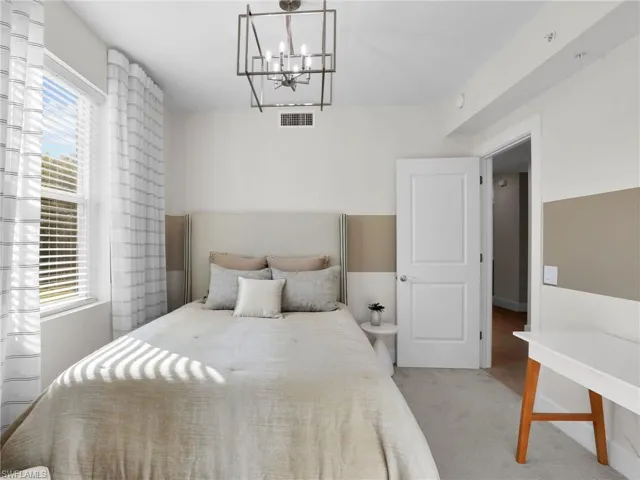 Carpeted bedroom with an inviting chandelier