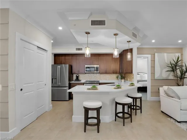 Kitchen with sink, appliances with stainless steel finishes, a kitchen breakfast bar, decorative backsplash, and decorative light fixtures