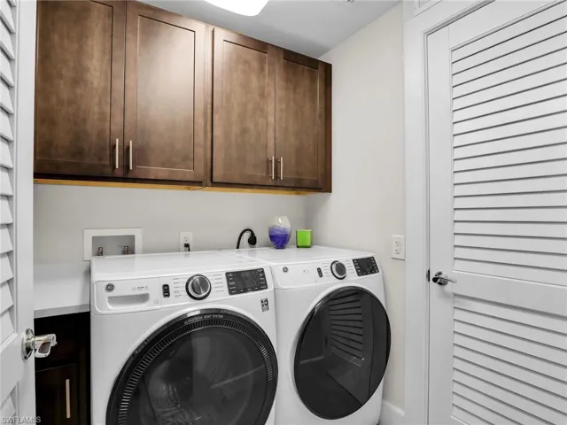 Laundry room with washer and clothes dryer and cabinets