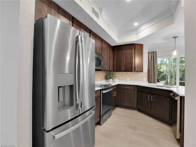 Kitchen with sink, tasteful backsplash, hanging light fixtures, a tray ceiling, and stainless steel appliances
