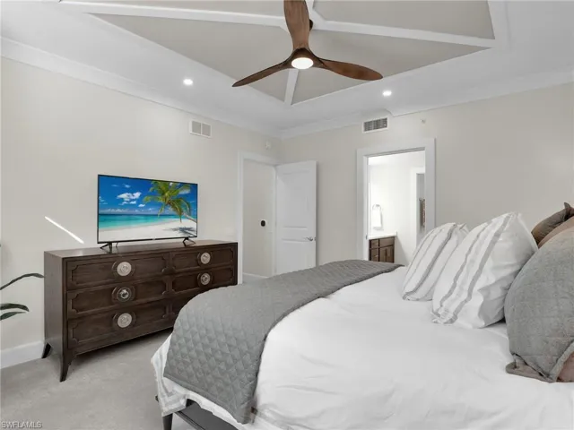 Bedroom with crown molding, ensuite bath, light colored carpet, and ceiling fan