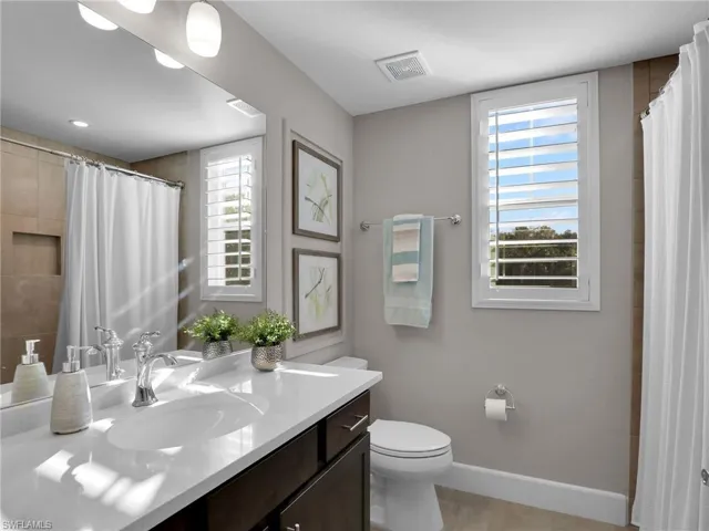 Bathroom with vanity, curtained shower, and toilet