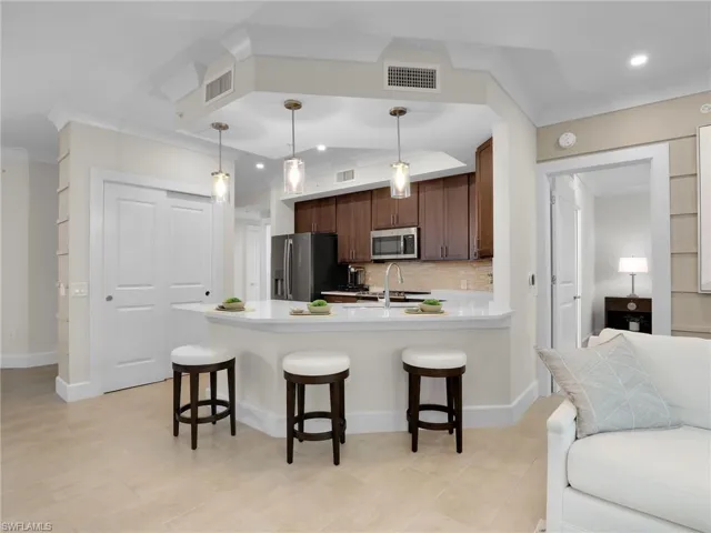 Kitchen with appliances with stainless steel finishes, pendant lighting, sink, backsplash, and a kitchen bar