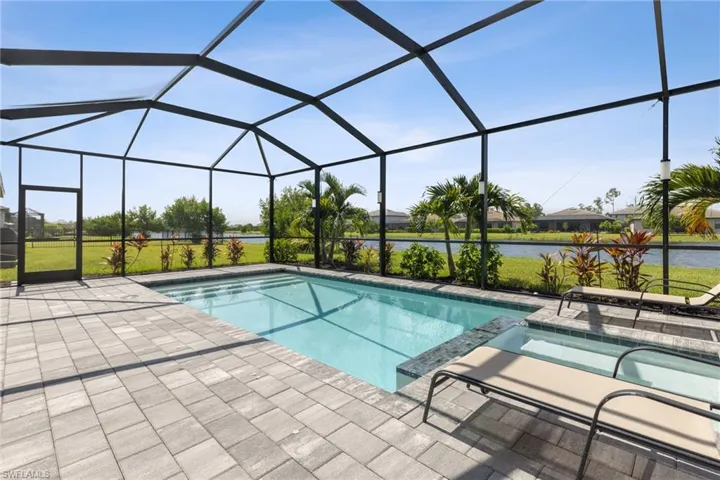 View of swimming pool with a patio, glass enclosure, and an in ground hot tub