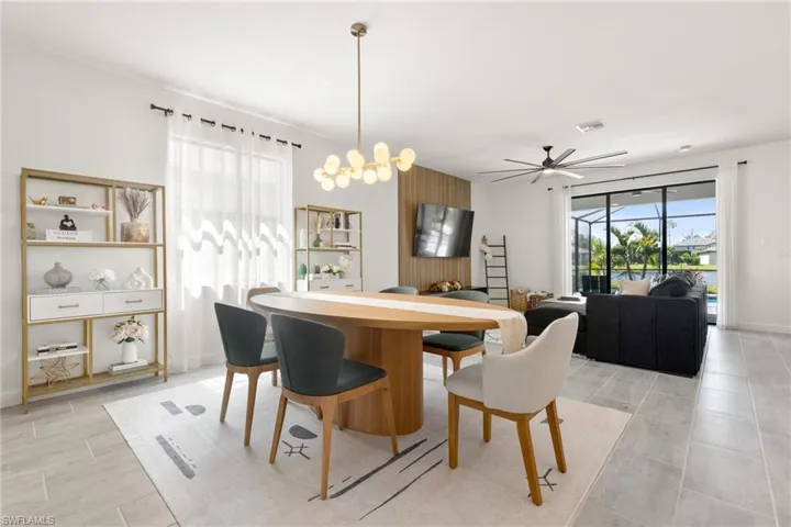 Tiled dining space featuring ceiling fan with notable chandelier