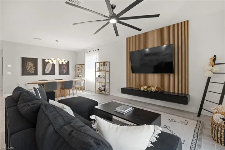 Tiled living room featuring ceiling fan with notable chandelier