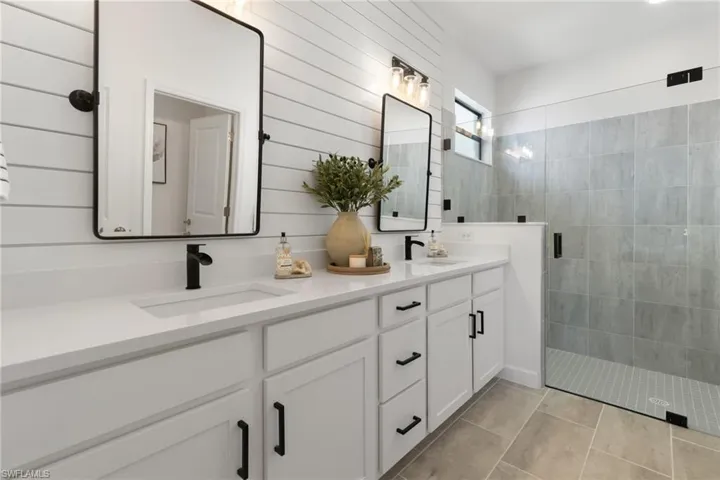 Bathroom with tiled shower and dual vanity
