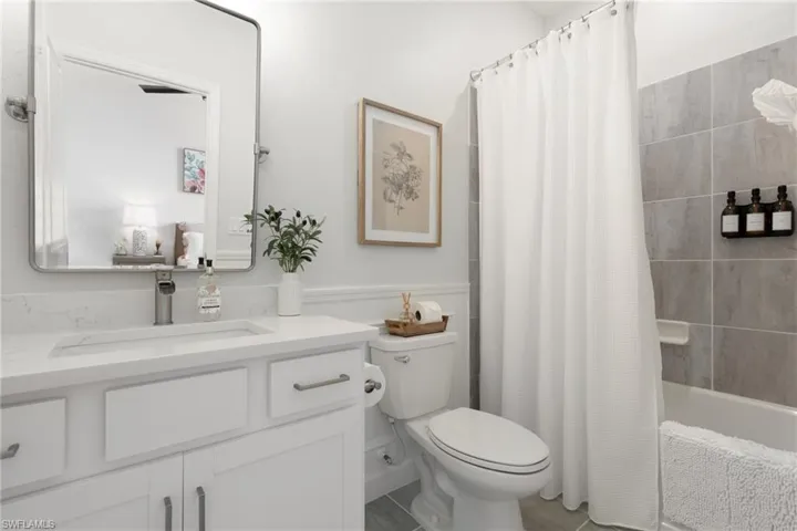 Full bathroom with tile patterned flooring, shower / bath combination with curtain, toilet, and vanity