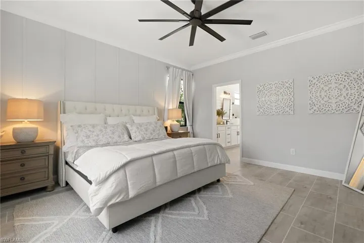 Bedroom featuring ceiling fan, ornamental molding, and ensuite bathroom