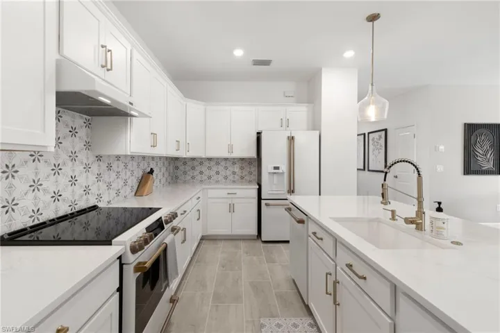 Kitchen featuring sink, tasteful backsplash, white cabinets, and high end appliances