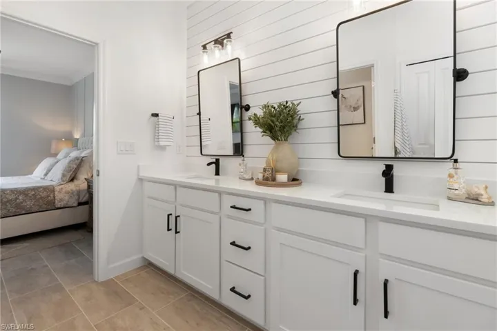 Bathroom featuring tile patterned flooring, double vanity, and crown molding