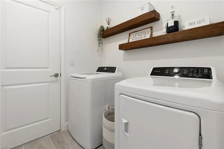 Laundry area with separate washer and dryer and light tile patterned floors