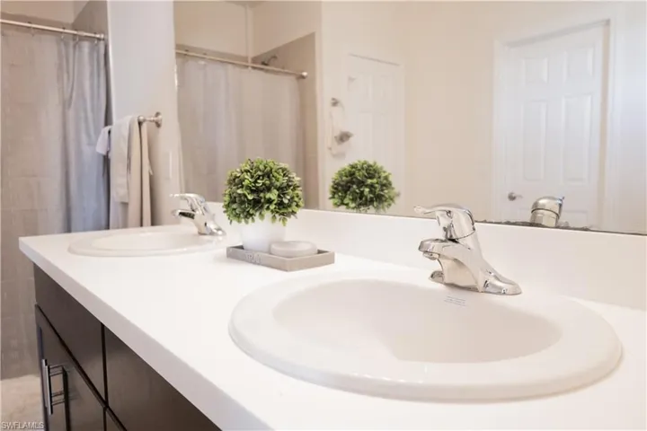 Bathroom with double vanity, a sink, and a shower with shower curtain