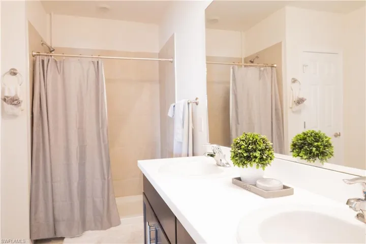 Bathroom with a shower with curtain, double vanity, and a sink