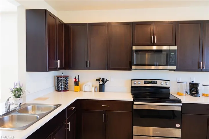 Kitchen with light countertops, dark brown cabinetry, a sink, and stainless steel appliances