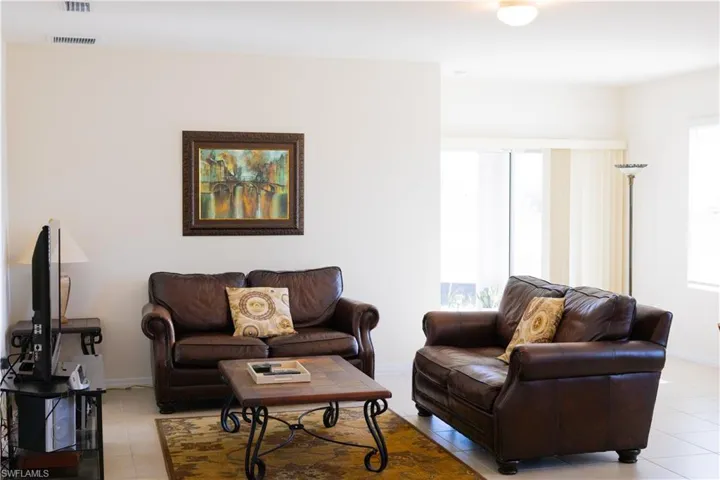 Living area featuring baseboards, visible vents, and light tile patterned floors