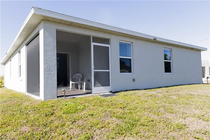 Rear view of property featuring a sunroom, stucco siding, and a yard