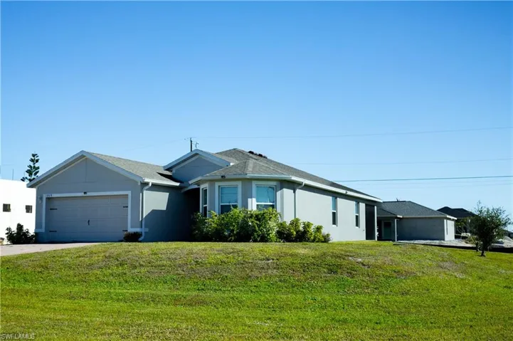 Ranch-style house featuring stucco siding, an attached garage, concrete driveway, and a front yard
