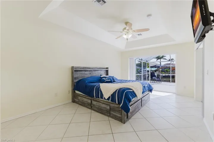 Bedroom featuring a raised ceiling, baseboards, and light tile patterned floors