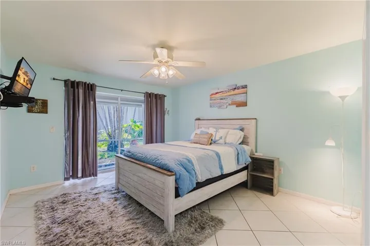Bedroom featuring light tile patterned floors, access to outside, baseboards, and a ceiling fan