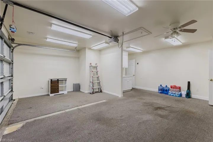 Garage with a garage door opener, ceiling fan, and baseboards