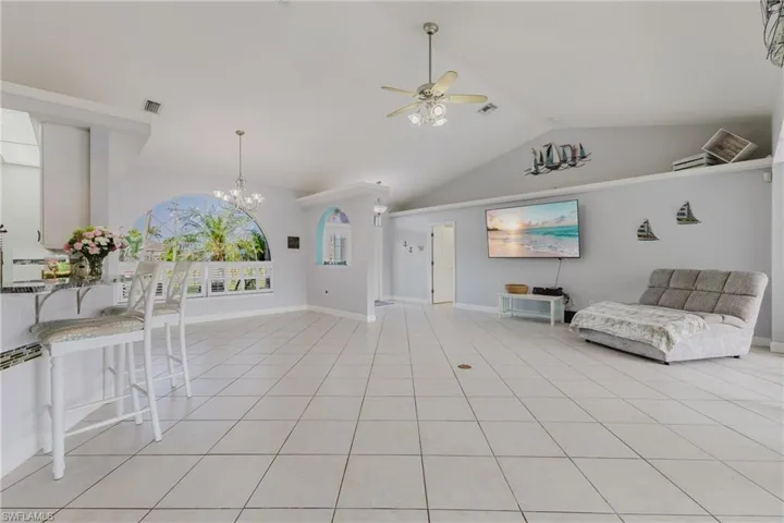 Living area featuring ceiling fan, lofted ceiling, a chandelier, baseboards, and light tile patterned floors