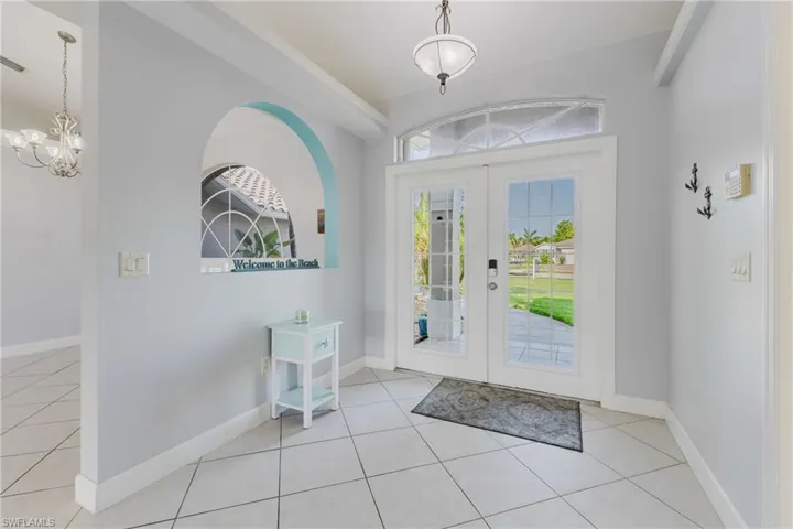 Tiled entrance foyer featuring a chandelier, baseboards, and french doors