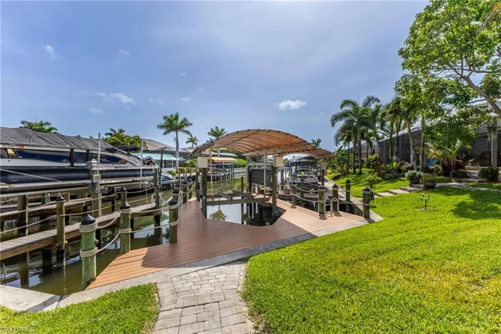 Dock area featuring boat lift, a lawn, and a water view