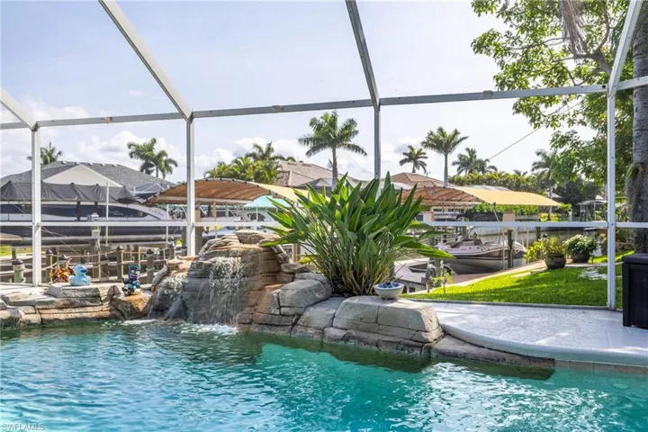 View of swimming pool with glass enclosure, a boat dock, and boat lift