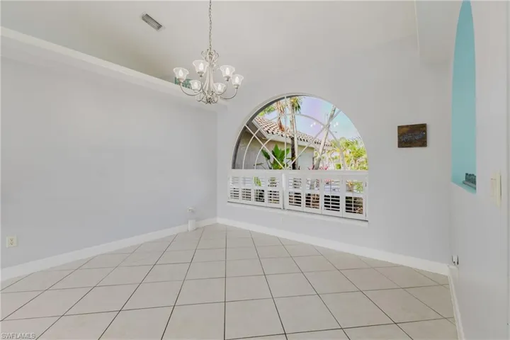 Tiled spare room with a chandelier and baseboards