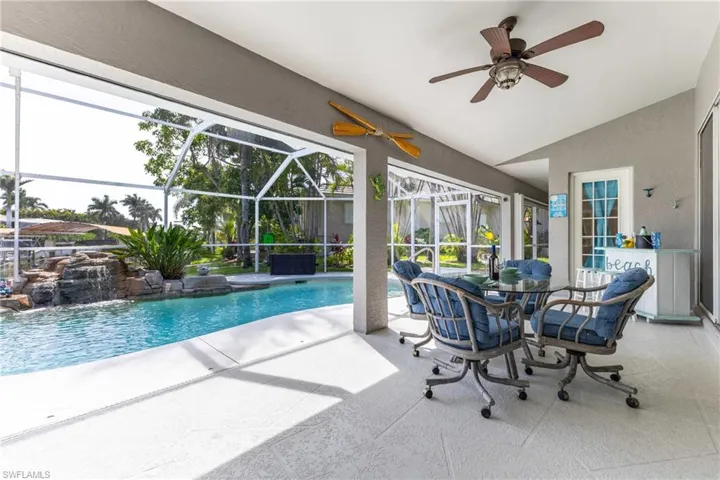 Swimming pool featuring a patio, a ceiling fan, and glass enclosure