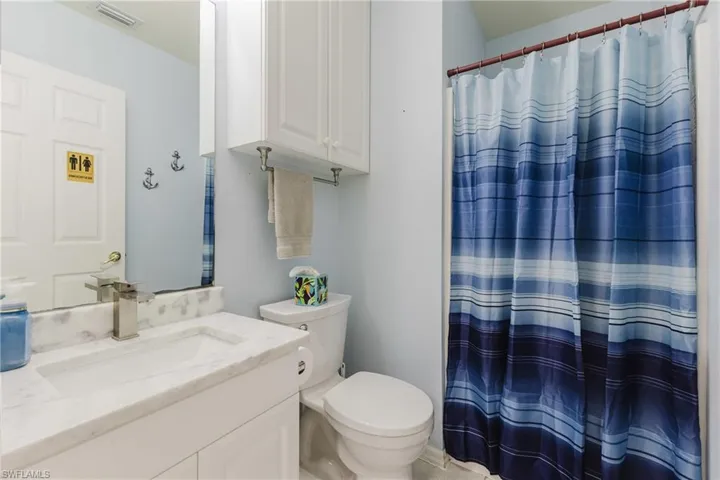 Bathroom featuring toilet, vanity, and a shower with curtain